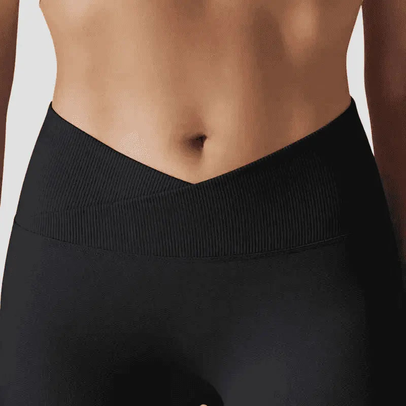 Cette image met en avant le détail de la taille haute en V du legging Elia. La ceinture présente une maille côtelée croisée élégante qui souligne la silhouette, tandis que le reste du vêtement affiche une finition lisse et opaque.